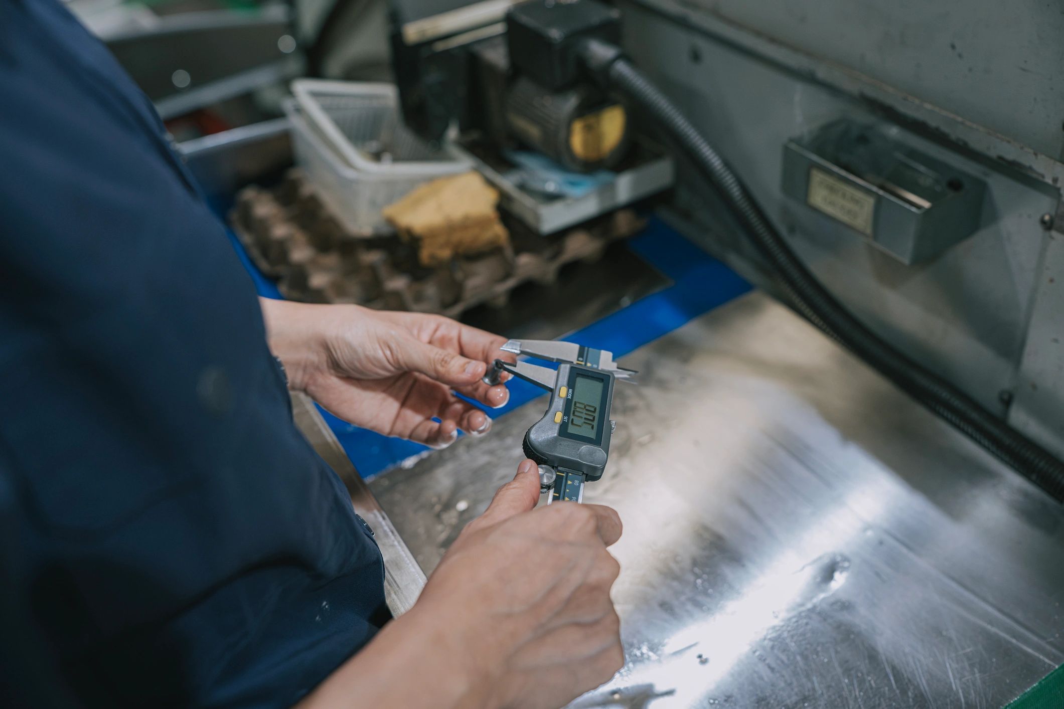 Technician measuring a machined metal part with calipers